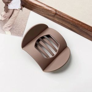 Macro shot of matte brown flat geometric hair claw with hollow slats and sleek texture