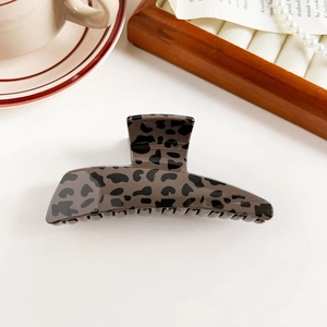 Macro detail of glossy leopard print claw clip with elegant bow and leopard patterns