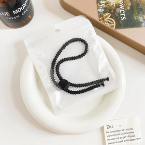Close-up of black braided elastic hair tie with matte buckle in minimal packaging