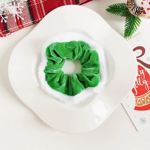 Dettaglio di scrunchie natalizio in velluto verde con ecopelliccia bianca su sfondo festivo