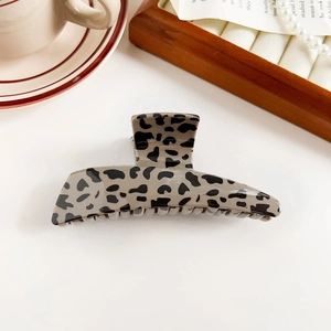 Macro shot of leopard print shark hair clip with retro bow design on white surface