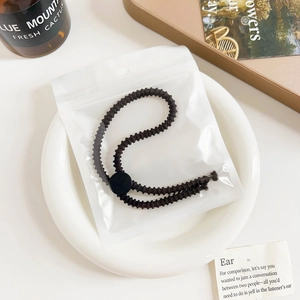 Brown threaded adjustable hair tie in frosted packaging placed on a ceramic plate