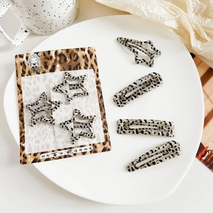 Detailliertes Set von Haarklammern mit Leopardenmuster in Sternform auf weißem Porzellanteller