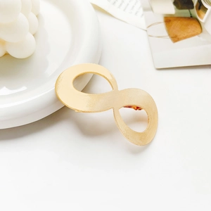 Detail of infinity-shaped golden metal hair clip with a textured matte finish