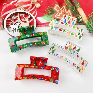 Lot de quatre pinces à cheveux de Noël avec motifs de sapins colorés sur une nappe festive