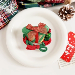 Détail du chouchou de Noël avec boîte cadeau verte en peluche, nœud rouge et cloches