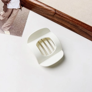 Close-up of cream matte hair claw clip with cutout design on a minimalist background