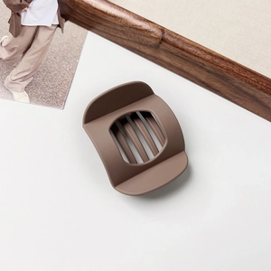 Detail of large matte mocha brown hair claw clip with a hollow geometric design