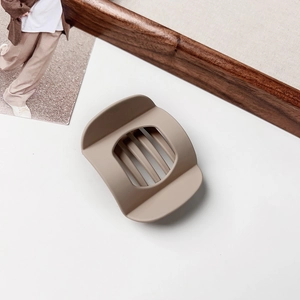 Detail shot of a matte brown rectangular claw clip featuring a hollowed vertical slat design