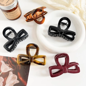 Detail of bow-shaped hair claws in assorted colors like black and amber on white decor