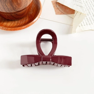 Detailed view of glossy burgundy bow hair claw clip on a vintage background