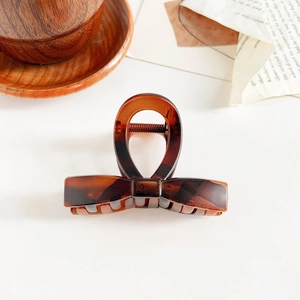Detail view of amber tortoiseshell hair claw clip with sturdy spring on white desk