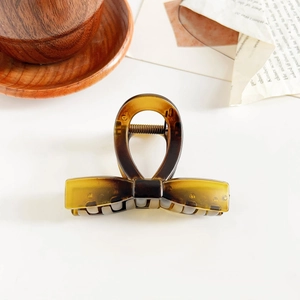 Detail view of amber textured claw clip with bow design on a minimalist background
