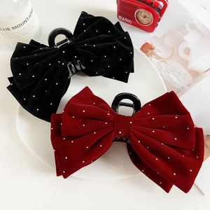 Detail of velvet bow hair claws with white rhinestone accents in black and burgundy