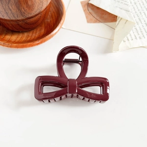 Detailed view of the glossy dark red bow hair claw clip with a strong metal spring