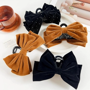 Close-up of velvet bow hair claws in black and caramel colors with pearl accents