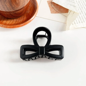 Close-up of matte black bow-shaped hair claw clip with a minimalist square buckle design