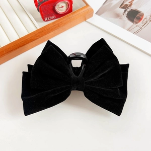 Detail of multi-layered black velvet bow hair claw clip on a vintage background