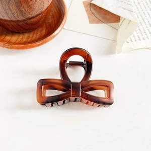 Detailed view of amber brown bow hair claw clip on vintage paper and wooden tray