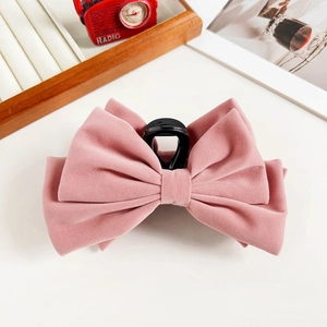 Detailed close-up of a pink velvet bow hair claw clip with a matte flocked texture
