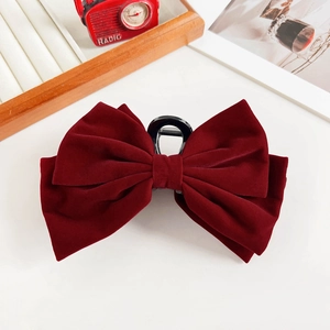 Macro shot of dark burgundy velvet bow hair claw clip showing soft fabric texture