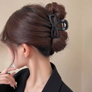 Minimalist matte black bow hair claw clip worn by a model for an elegant hairstyle