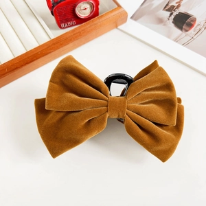 Detailed view of caramel velvet bow hair claw clip against a vintage radio prop background