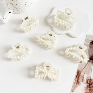 Detail showing six assorted faux pearl hair claws on cream resin bases for elegant styling