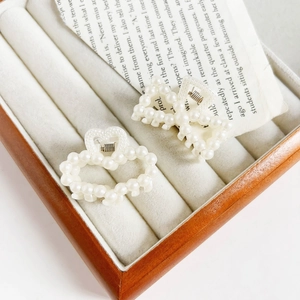 Detailed view of elegant pearl heart and rectangular hair clips on a jewelry tray