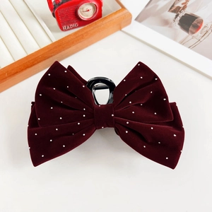 Detail of burgundy velvet hair claw with small silver rhinestones and large bow design
