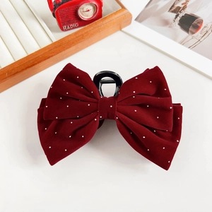 Macro view of burgundy velvet bow hair claw clip with delicate pearl accents