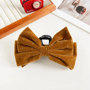 Macro detail of brown velvet bow hair claw clip with pearl accents for elegant hairstyles