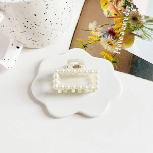 Detailed macro view of cream small pearl hair claw clip with elegant metal spring closure