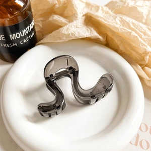 Close-up of translucent grey wave hair claw clip featuring a silver metal spring mechanism