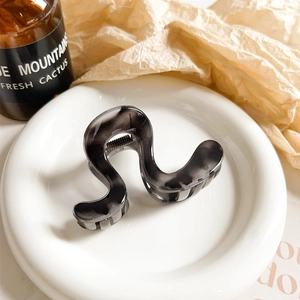 Detail view of wave-shaped marble hair claw clip with black and grey zebra patterns