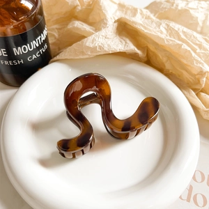 Detail view of a tortoiseshell hair claw clip with geometric waves on a ceramic plate