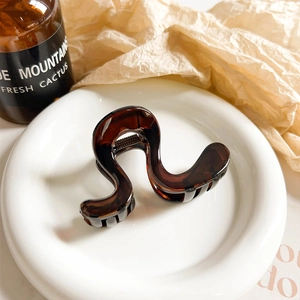 Close-up of S-shaped tortoiseshell hair claw clip with glossy resin and metal spring
