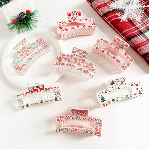 Detailed view of large Christmas hair claws featuring festive elk and snowflake prints