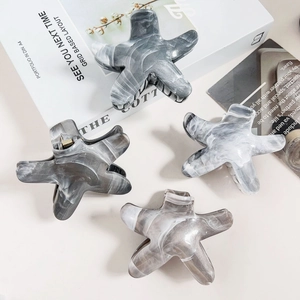 Detailed view of four grey and white marble pattern starfish hair claws with gold hardware