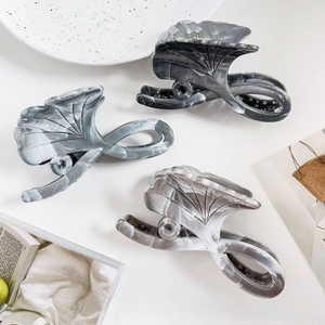 Detail view of large acetate claw clips with marble pattern in扇形 gingko leaf design