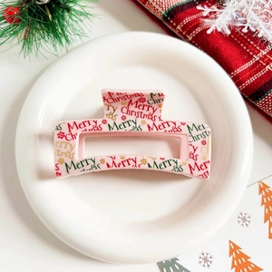 Detail of pink Christmas hair claw clip with Merry Christmas text on a festive tray