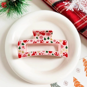 Detail of pink acetate hair claw clip with festive snowman and Christmas tree patterns