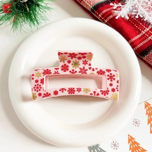 Detailed view of pink rectangular hair claw clip with red and gold snowflake patterns