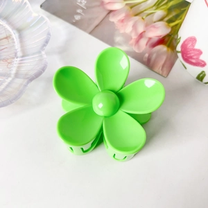 Détail d'une pince à cheveux fleur vert vif sur un fond décoratif minimaliste