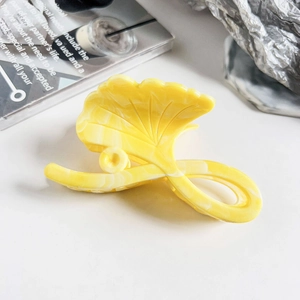 Detail of yellow ginkgo leaf hair claw with marble texture on a modern desk