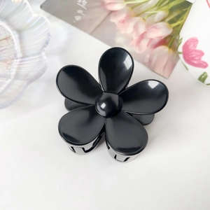 Vue détaillée d'une pince à cheveux noire brillante en forme de fleur sur fond blanc