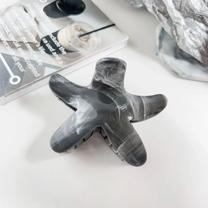 Close-up of marble pattern star hair claw clip with detailed spring mechanism