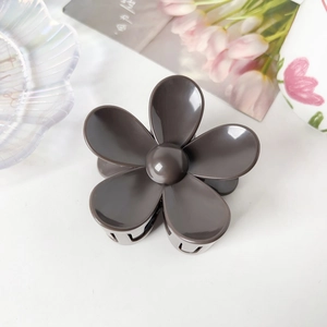 Gros plan détaillé d'une pince à cheveux fleur marron foncé sur fond décoratif élégant