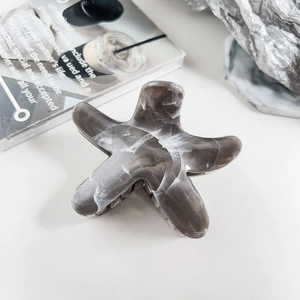 Macro detail of star-shaped grey marble hair claw clip with acetate finish on white background