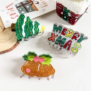 Detailed view of Christmas hair clips featuring a green tree, golden bell, and Merry Xmas text